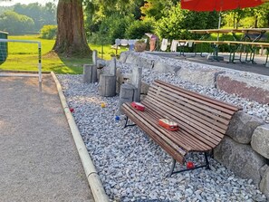 A park bench with a bag and a red object on it, surrounded by gravel and rocks. - Spacious house with spa and playground at the forest edge (Fraize)