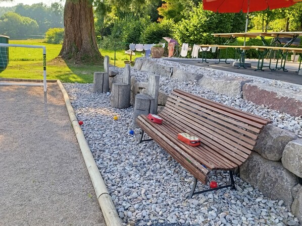 A park bench with a bag and a red object on it, surrounded by gravel and rocks.