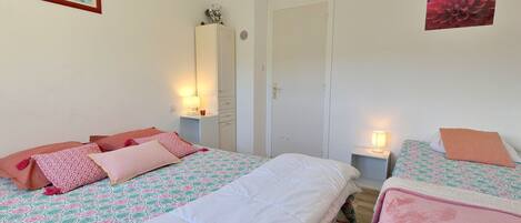 A bedroom with two beds, a wardrobe, a mirror, and a framed certificate on the wall.