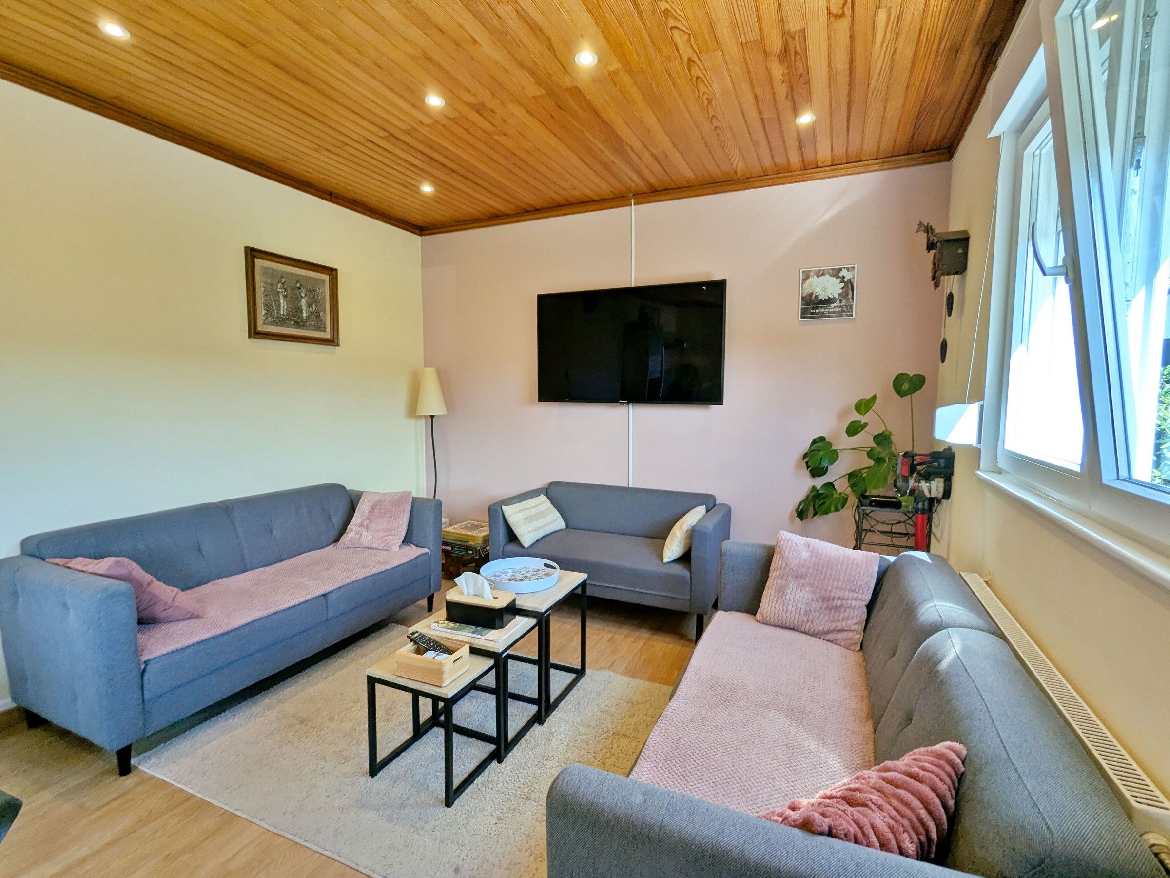 Una sala de estar con dos sofás, una mesa de centro, un televisor y un ventanal.