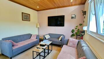 Una sala de estar con dos sofás, una mesa de centro, un televisor y un ventanal.