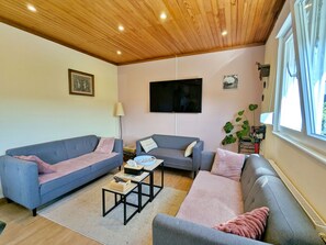 A living room with two sofas, a coffee table, a TV, and a window.
