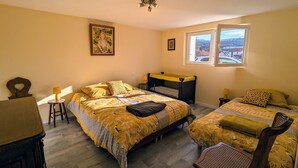 Een slaapkamer met twee bedden, een raam met uitzicht, een plafondlamp en een klein tafeltje.