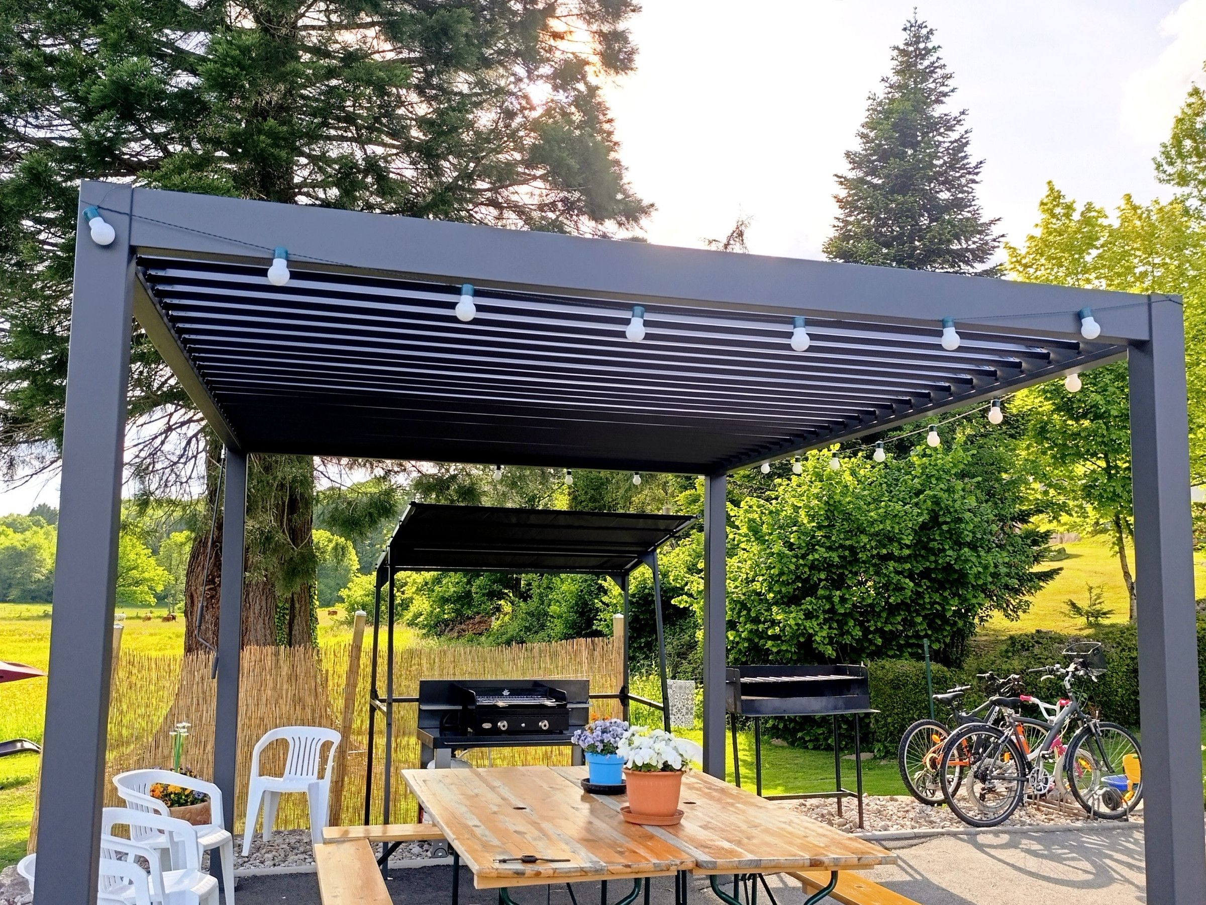 An outdoor patio with a wooden table, chairs, and a grill.