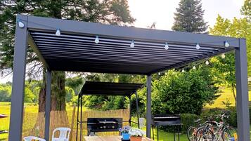 An outdoor patio with a wooden table, chairs, and a grill.