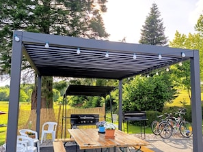 An outdoor patio with a wooden table, chairs, and a grill. - Spacious house with spa and playground at the forest edge (Fraize)