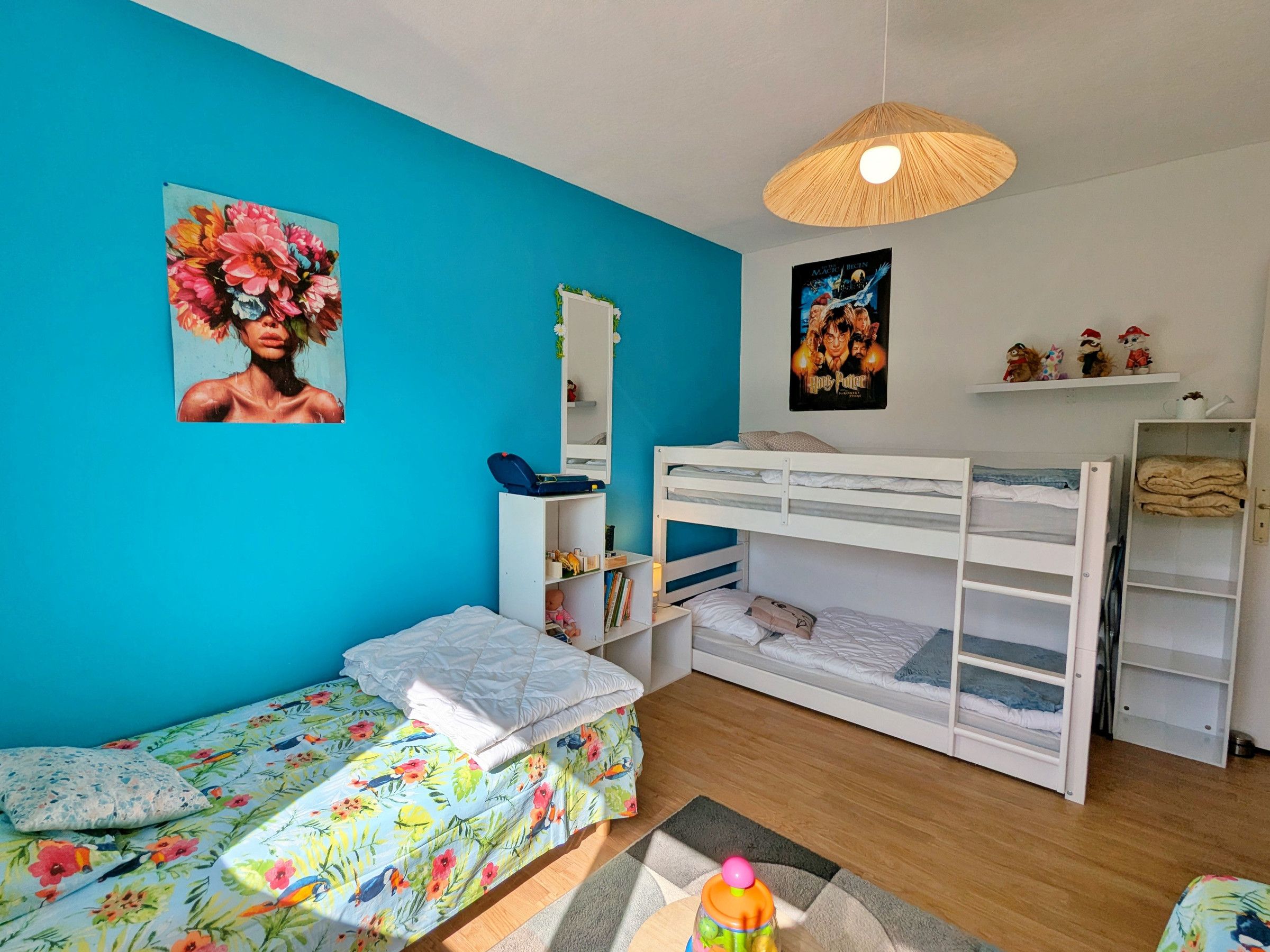 Ein Zimmer mit einem Etagenbett, einem Schreibtisch mit Stuhl, einem Spiegel und einem Poster an der Wand.