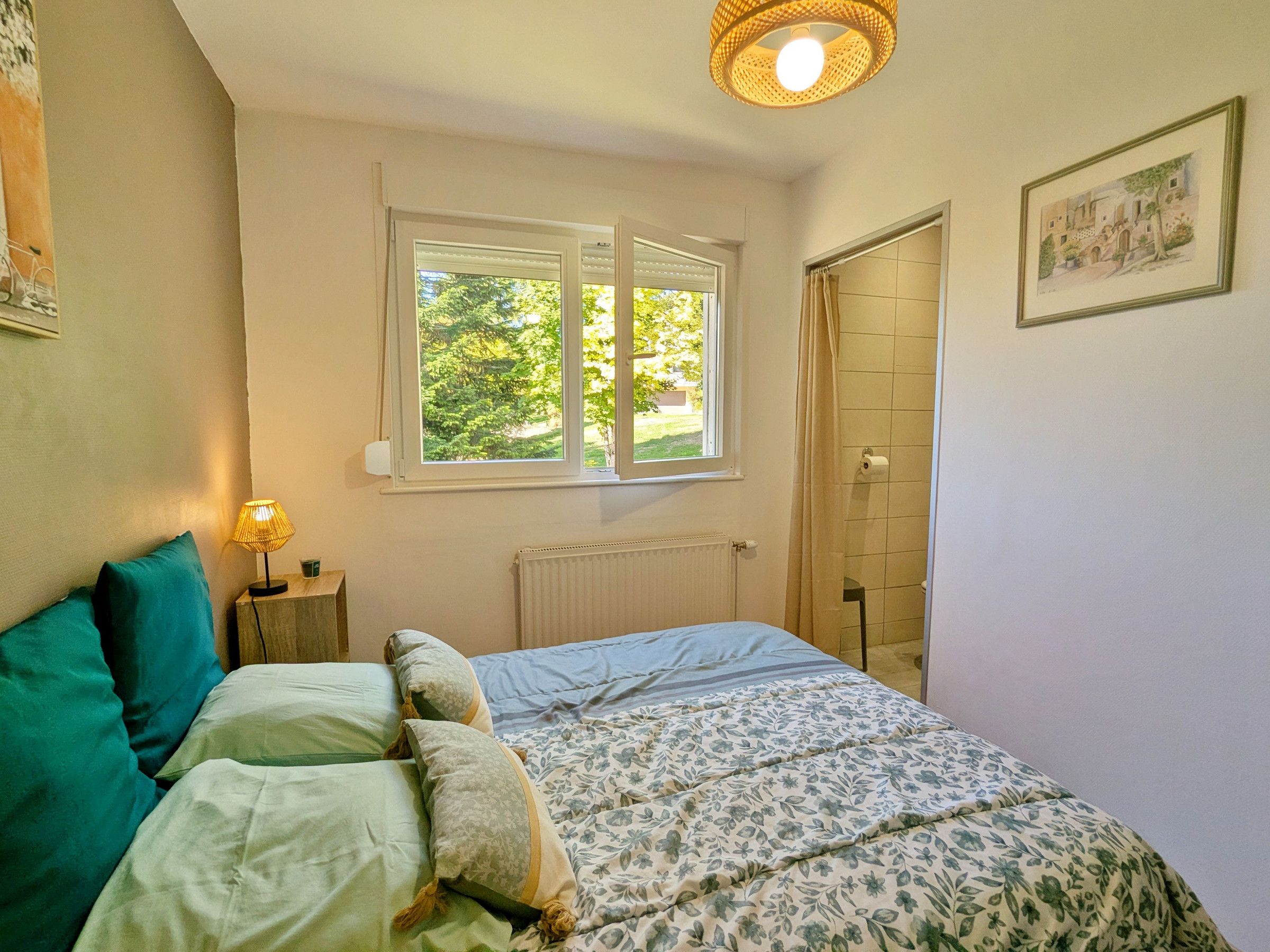 A bedroom with a bed, a window, a radiator, and a door.