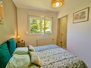 A bedroom with a bed, a window, a radiator, and a door.