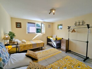 Une petite pièce agréable et confortable, avec deux lits, un bureau, une fenêtre et un ventilateur de plafond.