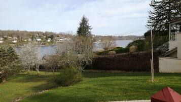 A residential area with a lawn, a red fire hydrant, and a view of a lake with houses in the background.