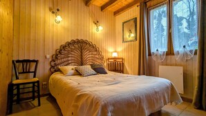 Een gezellige kamer met houten lambrisering, een groot bed, een stoel en een nachtkastje met een lamp.