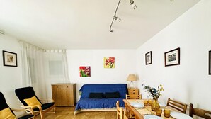 Un coin repas avec une table en bois dressée pour quatre personnes, un canapé bleu et un meuble en bois.