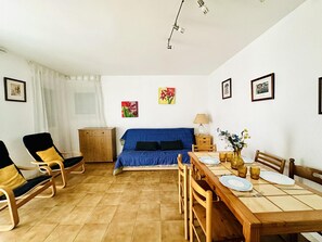 A dining area with a wooden table set for four, a blue sofa, and a wooden cabinet.