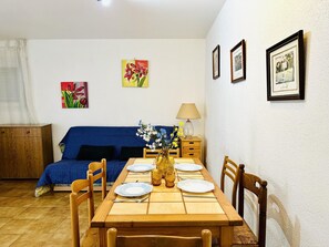A dining area with a wooden table set for four, a blue sofa, and a cabinet.