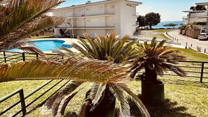 Un hotel con piscina, palmeras y vista al mar.