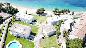 Vista aérea de un hotel costero con varias edificaciones, una piscina y una playa.