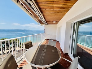 A balcony with a table and chairs, a view of the sea, and a wooden ceiling. - HORIZONTE AZUL. Frente al mar en la Playa de la Almadraba – Roses (Roses)