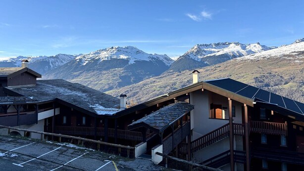 Un chalet de montagne offrant une vue sur les sommets enneigés.