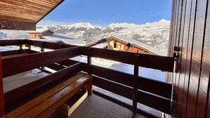 Un balcon en bois offrant une vue sur des montagnes enneigées.