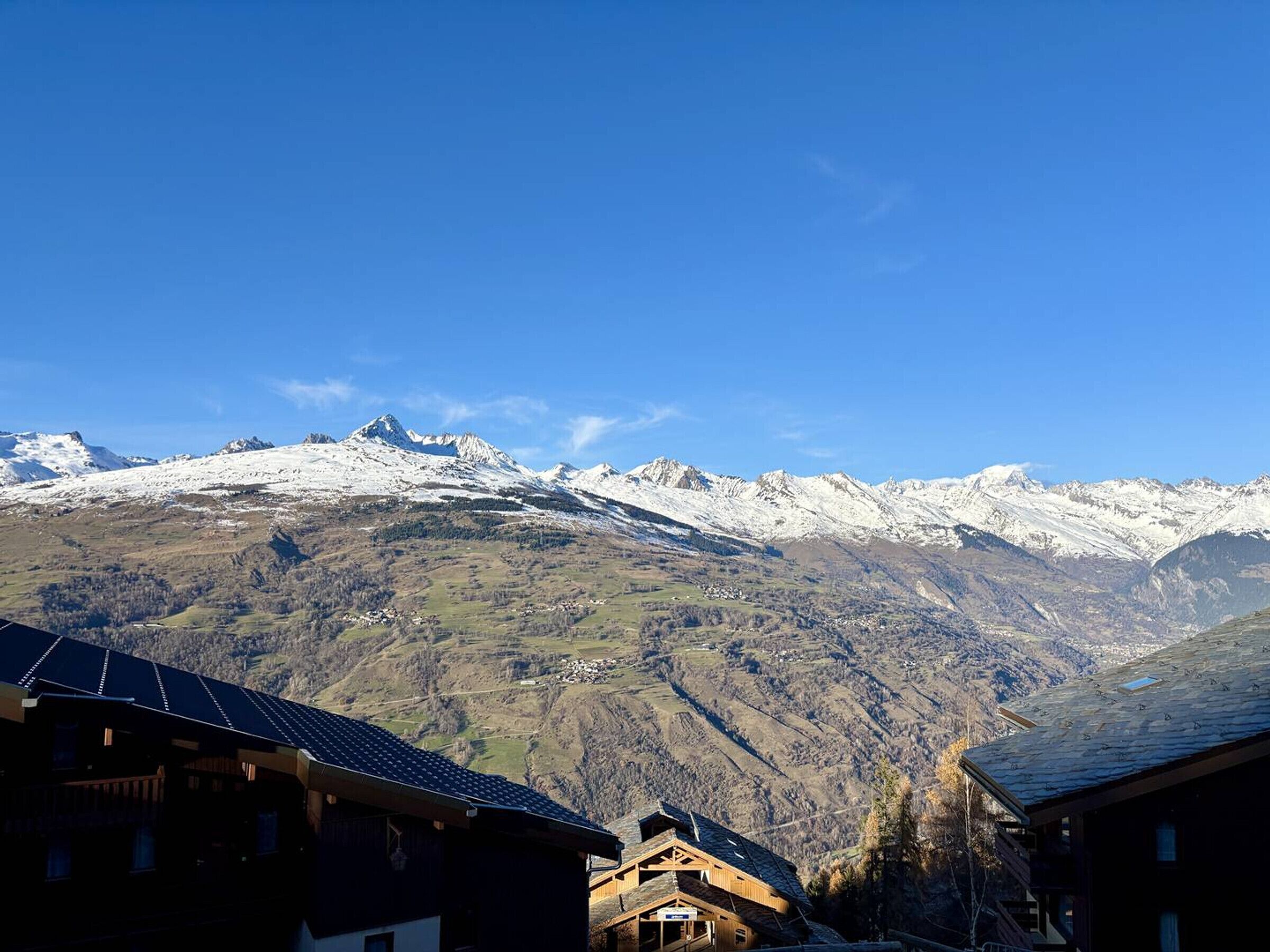 A mountain village with traditional wooden houses and a view of snow-capped peaks.