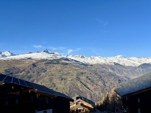 Un village de montagne aux maisons traditionnelles en bois, offrant une vue sur des sommets enneigés.