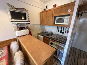 A compact kitchen with a microwave, toaster, and wooden cabinets.