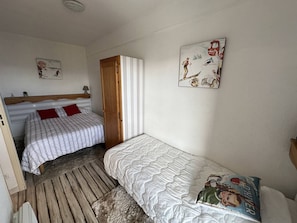 Una habitación con dos camas, una puerta de madera y un cuadro con temática de esquí.