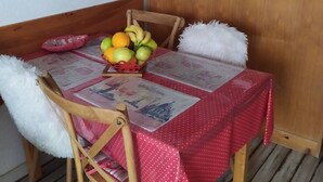Una taula de menjador amb un llençol vermell, una cistella de fruita i un diari.