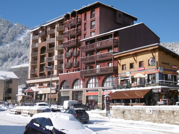 A multi-story building with balconies, a restaurant, and a parking area.