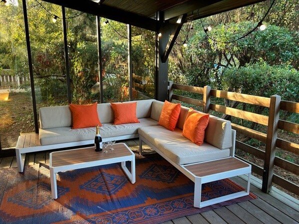 Un espace extérieur aménagé avec un canapé d’angle, une table basse et un tapis à motifs.