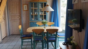 A wooden interior with a dining table, chairs, a cabinet, and a television. - Exklusives Skandinavisches Ferienhaus (Mirow)