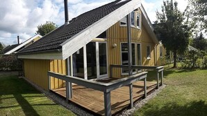 A wooden house with a sloped roof, large windows, and a deck. - Exklusives Skandinavisches Ferienhaus (Mirow)
