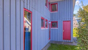 A modern building with a sloped roof and a small attached structure with a red door. - Skandinavisches Ferienhaus in Mirow (Mirow)