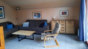 A living room with a sofa, a zebra-patterned chair, a wooden cabinet, and a table. - Ferienhaus im Skandinavischen Stil (Mirow)