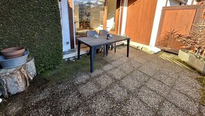 En terrasse med et bord og stole, et træhegn og udsigt til et bjerg.