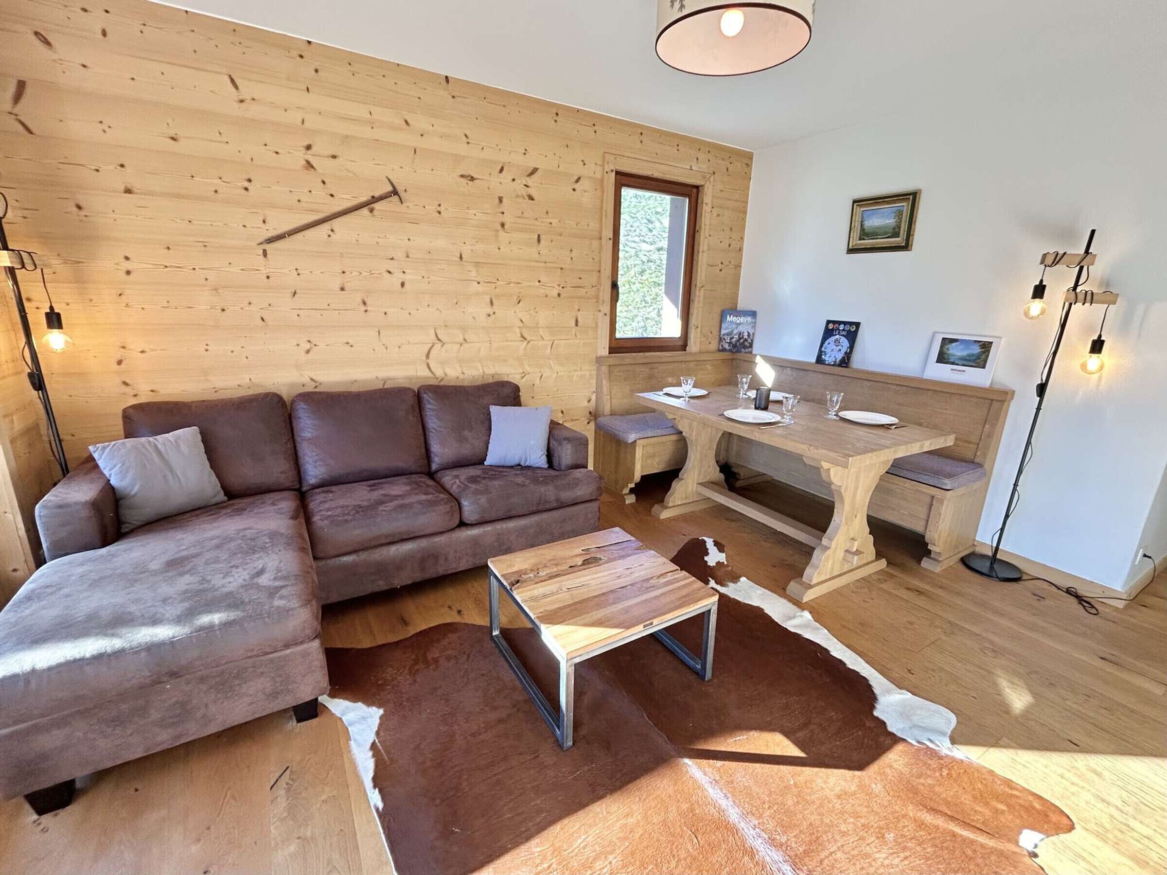 Un interno accogliente con una parete in legno, un divano in pelle marrone, un tavolo da pranzo per quattro e un tappeto in pelle di mucca.