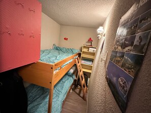 A small, compact room with a bunk bed, a desk, and a chair.
