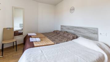 Una habitación de hotel con cama, una silla, un espejo y una lámpara fijada a la pared.