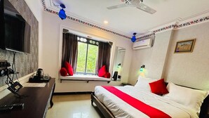 Ein Hotelzimmer mit Bett, Schreibtisch, Fernseher und einem Fenster mit Vorhängen.