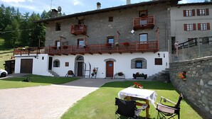A traditional stone building with a balcony, a garage, and a small outdoor seating area with a table and chairs.