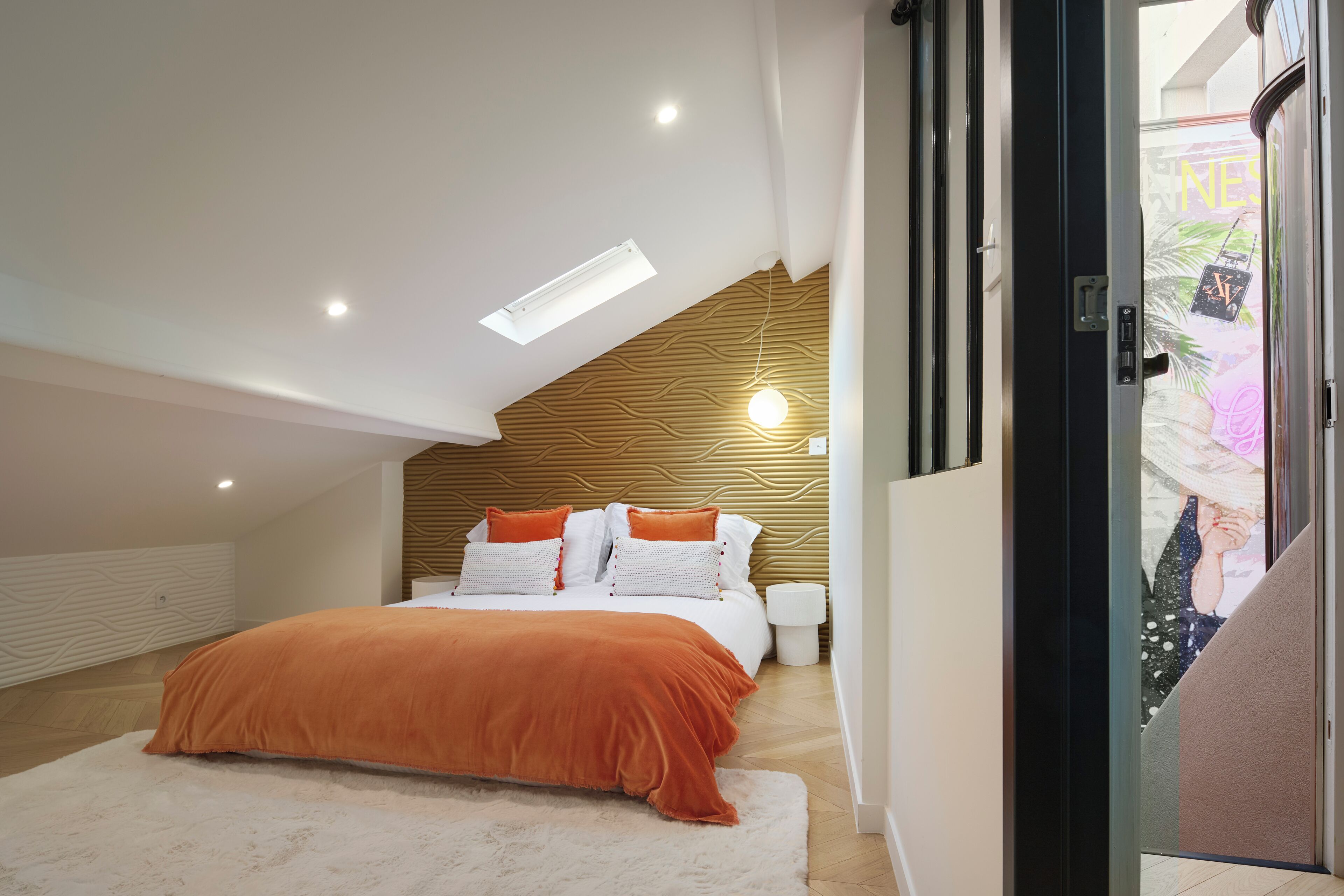 Un dormitorio moderno con techo inclinado, cama con ropa de cama naranja, alfombra blanca y pared de madera decorativa.