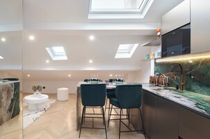 A modern kitchen with a marble countertop, a built-in oven, and a large window above the sink.