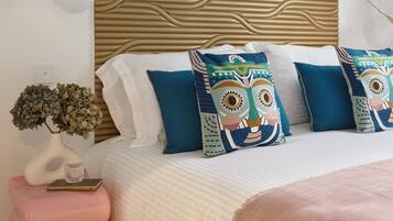 A bedroom with a bed, decorative pillows, a bedside table with a vase, and a wall with a textured pattern.