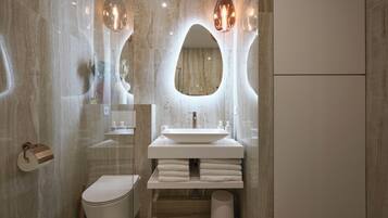 Une salle de bain moderne avec un grand miroir ovale, un lavabo blanc et des toilettes.