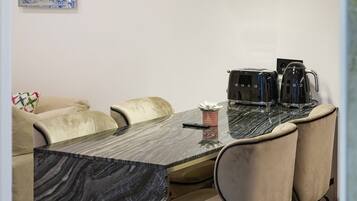 Un espace repas agrémenté d’une table en marbre, de chaises rembourrées et de luminaires suspendus.