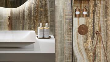 A bathroom with a marble vanity, a sink, and a shower area with a control panel.