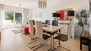 A modern dining area with a white table, black chairs, and a chandelier. - Apartment 'Sea View Close To The Beach' with Private Pool, Wi-Fi and Air Conditioning (Málaga)
