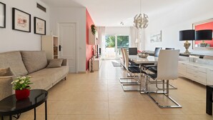 A modern living room with a sofa, dining table, chairs, and a coffee table. - Apartment 'Sea View Close To The Beach' with Private Pool, Wi-Fi and Air Conditioning (Málaga)