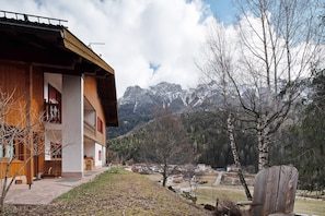 A wooden building with a balcony, a wooden chair, and a view of mountains. - Apartment 'Catinaccio' with Mountain View and Wi-Fi (Soraga di Fassa)